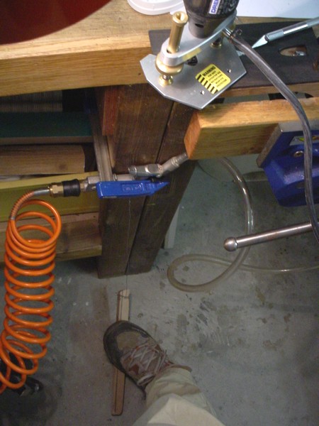 My set up for blowing compressed air while routing. The air blower is plugged in the air compressor. The wood stick is connected with a wire to the trigger of the blower and acts as a pedal.
