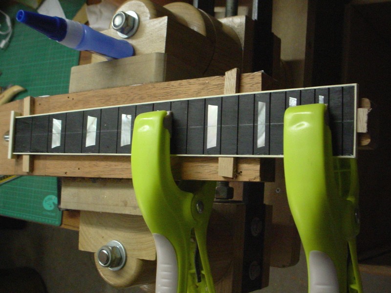 Une fois le binding installé, la touche est positionnée sur le manche, immobilisée avec les petites cales de bois collées à la CA.Technique Christophe Grellier.